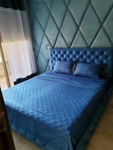 a blue bed with a blue headboard and pillows at très belle maison avec jardin et piscine in Saidia 