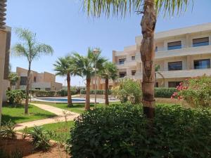 a palm tree in front of a building at très belle maison avec jardin et piscine in Saidia 