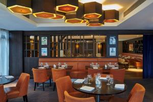 a restaurant with tables and chairs and a chandelier at DoubleTree by Hilton London Ealing in London