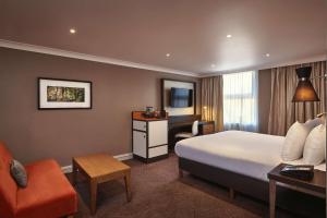 ロンドンにあるダブルツリー バイ ヒルトン ロンドン イーリングのベッドとデスクが備わるホテルルームです。