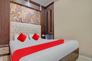 ein Schlafzimmer mit einem großen weißen Bett mit roten Kissen in der Unterkunft Flagship The Hangout Residency Inn in Jamshedpur