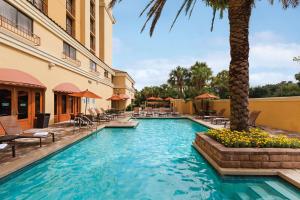 a swimming pool in a hotel with chairs and a palm tree at Embassy Suites by Hilton Orlando International Drive Convention Center in Orlando