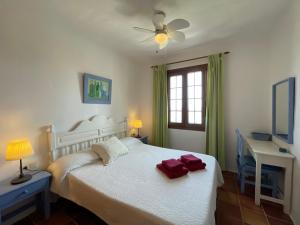 um quarto com uma cama branca e uma ventoinha de tecto em BERGANTIN 109 by SOM Menorca em Fornells