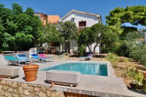a swimming pool in a yard with chairs and a house at Villa Barbat 28 in Barbat na Rabu