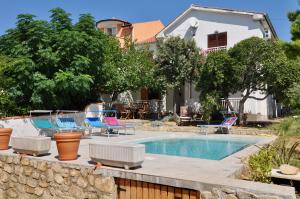 a swimming pool in a yard with chairs and a house at Villa Barbat 28 in Barbat na Rabu +31 photos