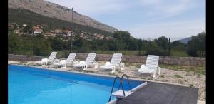 a group of white chairs and a swimming pool at Kamping Luke in Trebinje