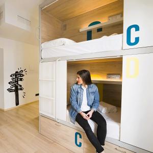 a woman sitting inside of a bunk bed at U-Sense For You Hostel Sevilla in Seville