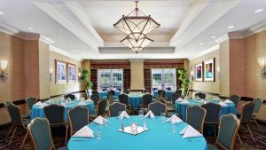 uma sala de conferências com mesas e cadeiras azuis e um lustre em Embassy Suites Parsippany em Parsippany