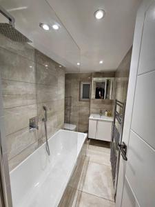 baño grande con bañera y lavamanos en cosy 1-Bed Apartment in London Alexandra Palace en Londres