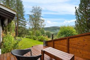 a wooden deck with a table and chairs on a balcony at Gaulabua - cozy cabin by the river Gaula 