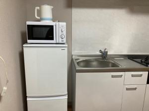 uma pequena cozinha com um micro-ondas em cima de um frigorífico em Sky Tree INN (晴樹宿）stay ASAKUSA em Tóquio