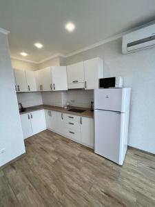 uma cozinha com armários brancos e um frigorífico branco em Sunny apartment в ЖК Сонячний Квартал em Golubinoye