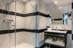 La salle de bains est pourvue d'une douche et d'un lavabo. dans l'établissement Niepce Paris, Curio Collection By Hilton, à Paris