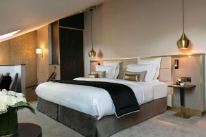 a bedroom with a large bed with white sheets and pillows at Niepce Paris, Curio Collection By Hilton in Paris