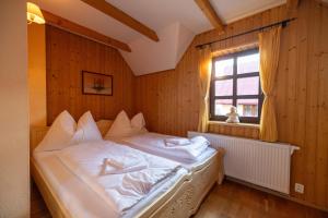 a bedroom with a bed with white sheets and a window at Chalupa Beliankovo in Ždiar