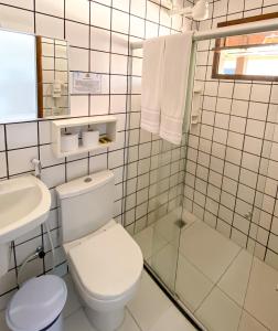 a white bathroom with a toilet and a sink at Hotel Malibu in Porto Seguro