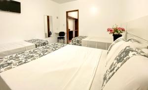 two beds in a room with white walls at Hotel Malibu in Porto Seguro