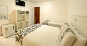um quarto branco com 2 camas e uma televisão em Hotel Malibu em Porto Seguro