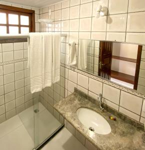 uma casa de banho com lavatório, espelho e toalhas em Hotel Malibu em Porto Seguro