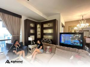 two women sitting on a couch in a living room at Alphatel Beach Hostel JBR in Dubai