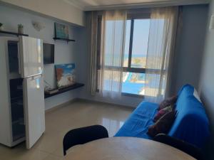 a living room with a blue couch and a large window at beach Apartments in Haifa