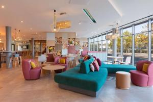 uma sala de estar com um sofá, mesas e cadeiras em Hampton by Hilton Ashford International em Ashford