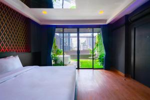 ein Schlafzimmer mit einem Bett und einem großen Fenster in der Unterkunft G Boutique Silom Hotel in Bangkok