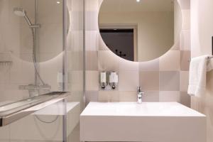a bathroom with a sink and a shower and a mirror at Hampton by Hilton Ashford International in Ashford +30 photos