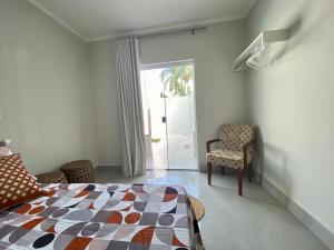 a bedroom with a bed and a chair and a window at Linda Casa com Piscina in Marília