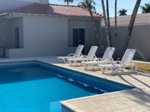 um grupo de cadeiras e uma piscina em Linda Casa com Piscina em Marília