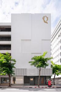 a white building with trees in front of it at G Boutique Silom Hotel in Bangkok