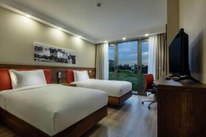 a bedroom with two beds and a desk and a television at Hampton by Hilton Canakkale Gelibolu in Gelibolu