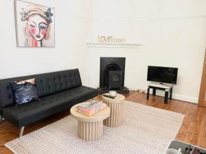 a living room with a black couch and a fireplace at Lurline Lodge in Katoomba