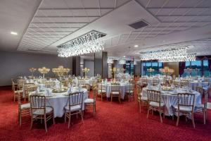 a banquet room with white tables and chairs and chandeliers at Hampton by Hilton Canakkale Gelibolu in Gelibolu