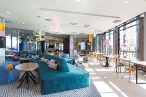 a lobby with a blue couch and tables and chairs at Hampton by Hilton Krakow Airport in Balice