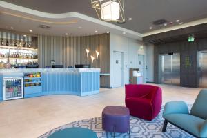 a lobby with a bar and a red chair at Hampton by Hilton Krakow Airport in Balice