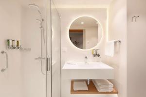 a white bathroom with a sink and a mirror at Hampton by Hilton Krakow Airport in Balice