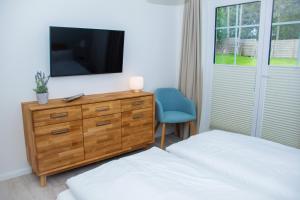 a bedroom with two beds and a dresser with a television at Cottage im Gutspark, Perlie - Komfort trifft maritimes Flair in Rerik