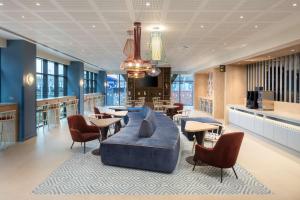 a lobby with a blue couch and tables and chairs at Hampton By Hilton Rochdale in Rochdale