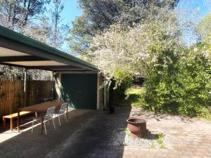 patio ze stołem i krzesłami pod drzewem w obiekcie Lurline Lodge w mieście Katoomba