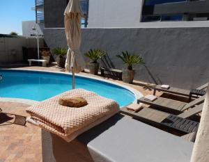 sombrilla y tumbonas junto a la piscina en Maartens Guesthouse en Ciudad del Cabo