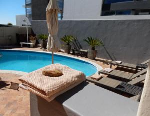 um guarda-sol e espreguiçadeiras ao lado de uma piscina em Maartens Guesthouse na Cidade do Cabo