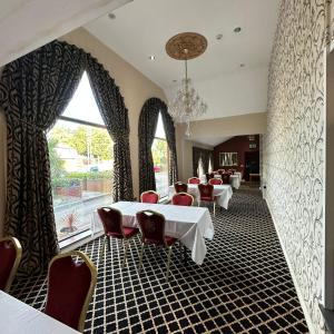 ロザラムにあるCarlton Park Hotel Rotherhamのテーブルと椅子、大きな窓のあるレストラン