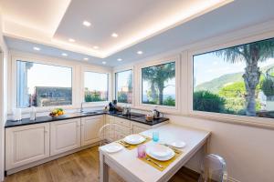 a kitchen with large windows and a table and chairs at Mary’s Guest House in Vico Equense