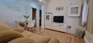 sala de estar con sofá, TV y mesa en Piso familiar y con encanto, en Sevilla