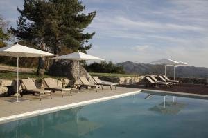 a swimming pool with lounge chairs and umbrellas next to it at Gerês - Leiras do Tempo - Cottages in Brufe