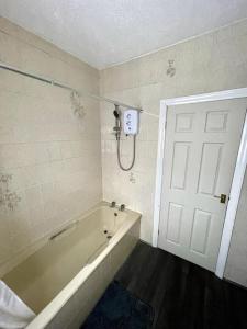 a bathroom with a tub and a white door at Stylish Four Bed City Retreat in Birmingham