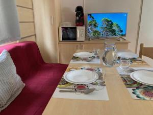 una mesa con platos y vasos encima en Mobil home Confortable et Lumineux 50 min de Paris, en Mirgaudon