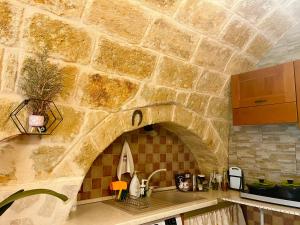 a stone kitchen with a sink and a stone wall at Cattleya in Mola di Bari