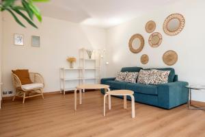 a living room with a blue couch and two tables at Apartments Sata Sagrada Familia Area in Barcelona